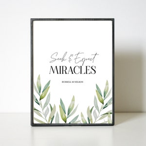 May include: A framed print with a white background and green watercolour leaves. The text reads "Seek & Expect MIRACLES" with "RUSSELL M. NELSON" in smaller font below.