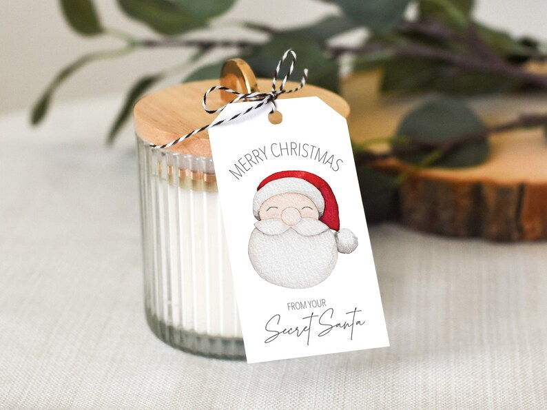 May include: White gift tag with a cartoon Santa Claus illustration. The tag says "Merry Christmas" and "From your Secret Santa".