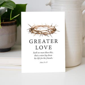 May include: A white rectangular card featuring a brown crown of thorns illustration at the top. Below the image, the text reads: GREATER LOVE hath no man than this, that a man lay down his life for his friends. John 15:13 in black serif font.