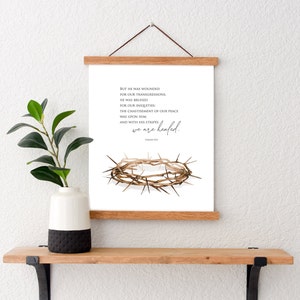 May include: A printable wall art design featuring a crown of thorns with the text "BUT HE WAS WOUNDED FOR OUR TRANSGRESSIONS, HE WAS BRUISED FOR OUR INIQUITIES: THE CHASTISEMENT OF OUR PEACE WAS UPON HIM, AND WITH HIS STRIPES WE ARE HEALED."