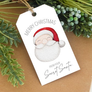 May include: White gift tag with a watercolor illustration of Santa Claus with a red hat and white beard. The text on the tag reads "Merry Christmas" and "From your Secret Santa".