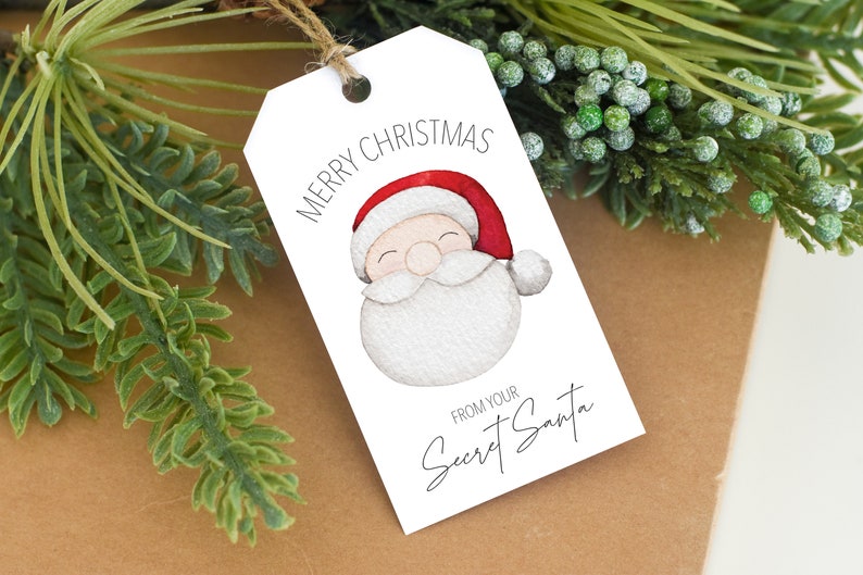 May include: White gift tag with a watercolor illustration of Santa Claus with a red hat and white beard. The text on the tag reads "Merry Christmas" and "From your Secret Santa".