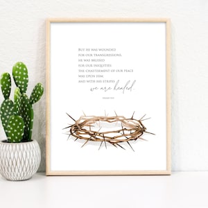 May include: A framed print with a watercolor illustration of a crown of thorns. The print features the Bible verse Isaiah 53:5, "But he was wounded for our transgressions, he was bruised for our iniquities: the chastisement of our peace was upon him: and with his stripes we are healed."