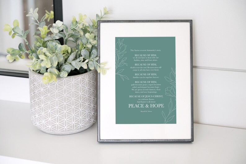 May include: A teal framed print with a white background and white floral designs. The text reads "The Savior's love illuminates our lives... BECAUSE OF HIM, we should love one another with pure hearts, minds, and strength, BECAUSE OF HIM, death is not the end, because every soul will come to all who have loved him, BECAUSE OF HIM, families can be together eternally, BECAUSE OF HIM, grief and sorrow become hope, relief, and peace, BECAUSE OF HIM, we are given strength, courage, and hope, joy, peace, and new beginnings, BECAUSE OF JESUS CHRIST, All Love is all around, PEACE & HOPE, David M. Stevenson"