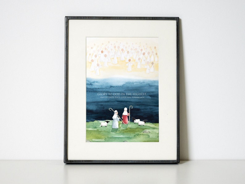 May include: Framed watercolor art print featuring a religious scene. The artwork depicts angels, shepherds, and sheep under a blue and yellow sky. The text "Glory to God in the highest, and on earth peace, good will toward men" is included.