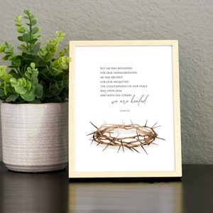 May include: A white framed print with a brown crown of thorns and a quote from Isaiah 53:5. The quote reads "But he was wounded for our transgressions, he was bruised for our iniquities: the chastisement of our peace was upon him: and with his stripes we are healed."