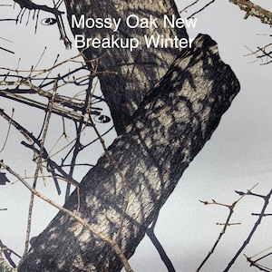 May include: A close-up of a camouflage pattern with the text "Mossy Oak New Breakup Winter". The pattern features a mix of brown, gray, and white, resembling tree bark and branches. The design is suitable for outdoor activities.