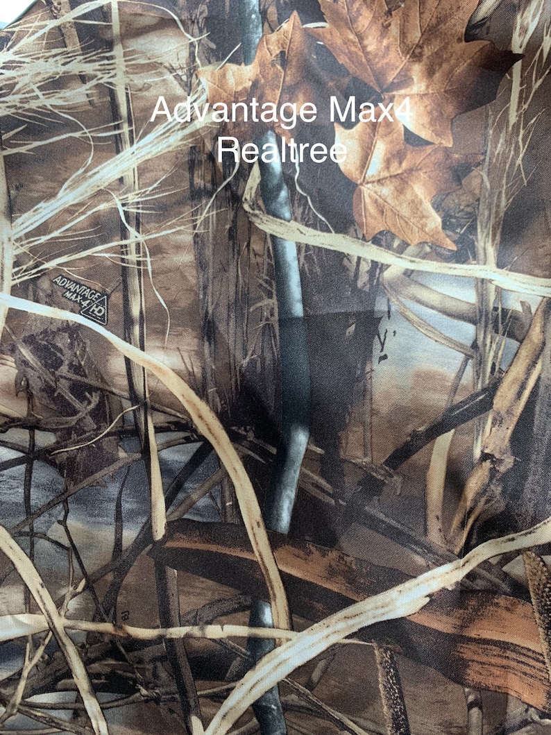 May include: Camouflage fabric featuring a blend of brown, tan, and green hues, with a pattern of leaves, branches, and other natural elements. The text "Advantage Max4 Realtree" is visible on the fabric. This design is commonly used for hunting and outdoor apparel.