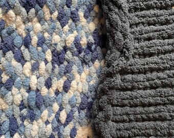 Può includere: Due coperte con texture diverse, una con un motivo blu e bianco e l'altra di colore grigio.