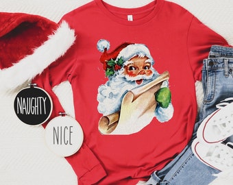 May include: Red long-sleeved t-shirt featuring a vintage illustration of Santa Claus holding a scroll that says "Naughty or Nice".