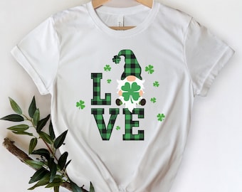 May include: White t-shirt with a green and black plaid gnome holding a shamrock and the word "LOVE" in green and black plaid.