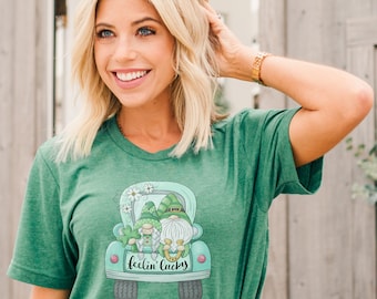 May include: Green t-shirt with a graphic of two gnomes in a green truck with white flowers and the text "feelin' lucky".