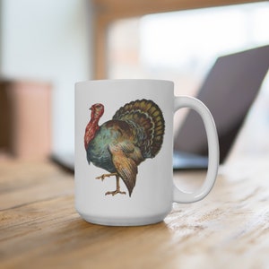 Puede incluir: Taza de caf&eacute; de cer&aacute;mica blanca con una ilustraci&oacute;n colorida de un pavo en la parte delantera.