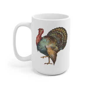 Puede incluir: Taza de caf&eacute; de cer&aacute;mica blanca con una ilustraci&oacute;n colorida de un pavo. El pavo tiene la cabeza roja, plumas azules y verdes y plumas de cola marrones y doradas.