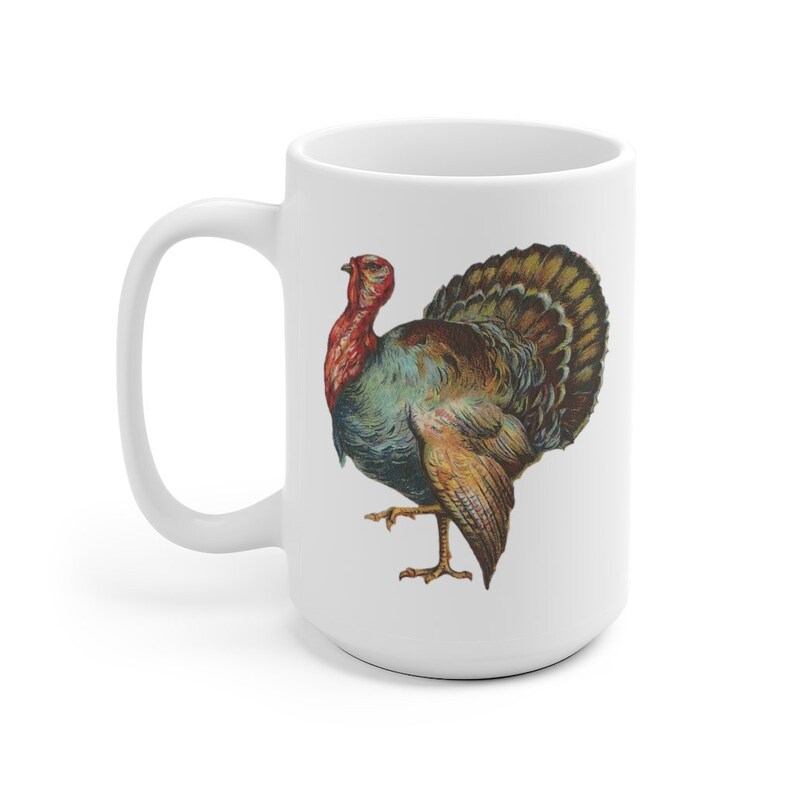 Puede incluir: Taza de caf&eacute; de cer&aacute;mica blanca con una ilustraci&oacute;n colorida de un pavo. El pavo tiene la cabeza roja, plumas azules y verdes y plumas de cola marrones y doradas.