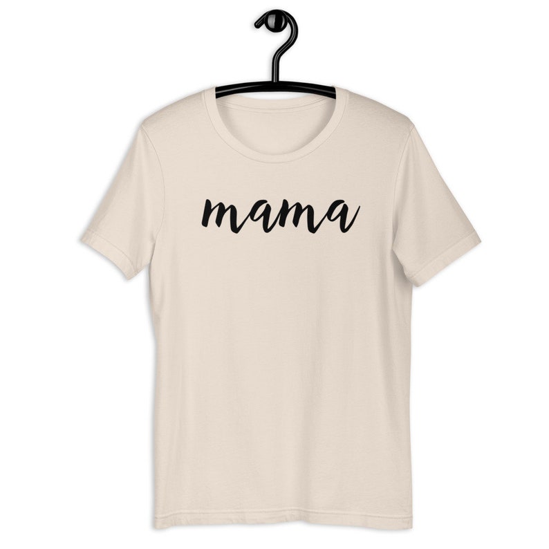 Może przedstawiać: Beżowa koszulka z napisem "mama" napisanym czarnym, ozdobnym pismem.