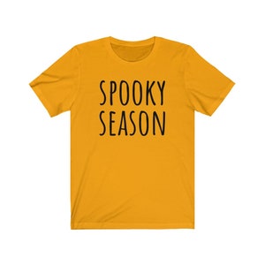 May include: A yellow short-sleeved t-shirt with the text "SPOOKY SEASON" printed in black.