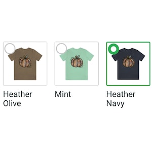 May include: Three t-shirts with a colorful pumpkin graphic. The t-shirts are in heather olive, mint, and heather navy.