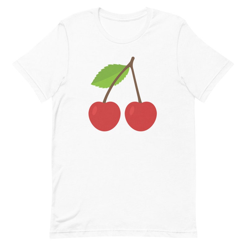 May include: White t-shirt with a cartoon illustration of two red cherries, a green leaf, and a brown stem. The cherries are circular and shiny. The t-shirt is made of a soft material.