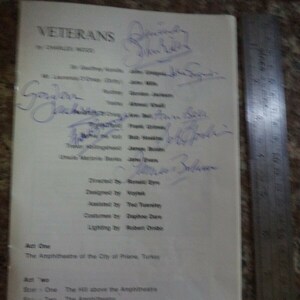 May include: A black and white playbill for a production of "Veterans" by James Wood. The playbill lists the cast and crew, including the director, designer, and lighting designer. The play is set in the Amphitheatre of the City of Priene, Turkey.