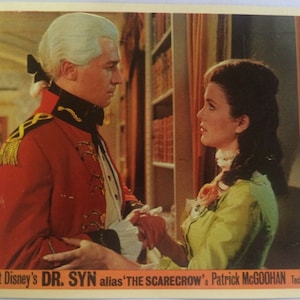May include: A black and white movie poster for Walt Disney's "Dr. Syn" starring Patrick McGoohan. The poster features a man in a red military uniform and a woman in a green dress. The text on the poster reads "Walt Disney's Dr. Syn alias 'The Scarecrow' Patrick McGoohan Technicolor."