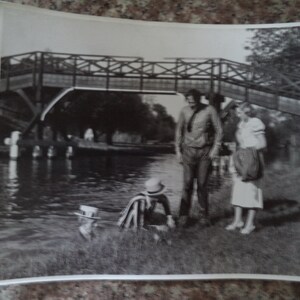 Puede incluir: Una fotografía en blanco y negro de cuatro personas de pie en un puente sobre un río. Las personas visten ropa informal y parecen estar disfrutando del aire libre.