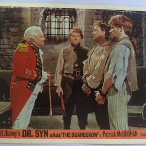 Könnte beinhalten: Ein Schwarzweiß-Filmplakat für den Film "Dr. Syn" mit Patrick McGoohan. Das Plakat zeigt eine Szene aus dem Film mit vier Männern in einer Gefängniseinstellung. Der Text auf dem Plakat lautet "Walt Disney's Dr. Syn alias 'The Scarecrow' Patrick McGoohan Technicolor."