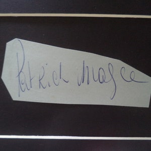 May include: A white piece of paper with a blue ink signature that reads "Patrick Magee".