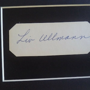 以下が含まれることがあります： Liv Ullmann と書かれた青いインクの署名が入った白いカードです。
