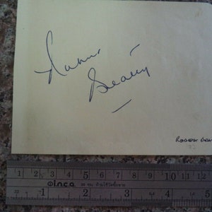 May include: A white card with a blue ink signature that reads "Lorna  Seay" and the text "RODOST DOATTY" in blue ink.