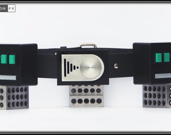 May include: A black device with a silver center panel and a black leather strap. The device has green and red buttons on each side, and is supported by metal blocks. The text "BLACK FALCON FX" is in the upper left corner.