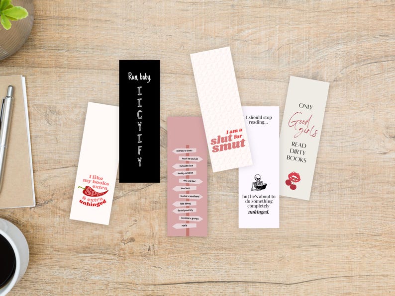 May include: A collection of rectangular bookmarks with various designs and text. One bookmark is black with white text, another is white with a red chili pepper graphic, and others have phrases like "I am a slut for smut" and "Read dirty books."