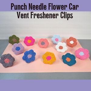 May include: A collection of colorful, punch needle flower car vent freshener clips. The flowers are in various colors, including pink, blue, yellow, and green, with contrasting center colors. The text "Punch Needle Flower Car Vent Freshener Clips" is at the top.