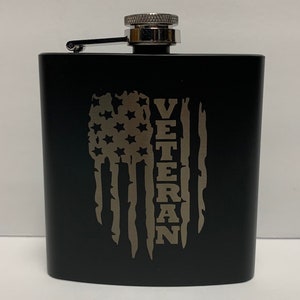May include: Black stainless steel flask with a silver cap and a silver engraved American flag with the word "Veteran" on the side.