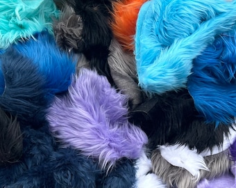 May include: A variety of faux fur fabrics in different colors, including blue, teal, purple, and black. The fabrics are piled together in a random arrangement.