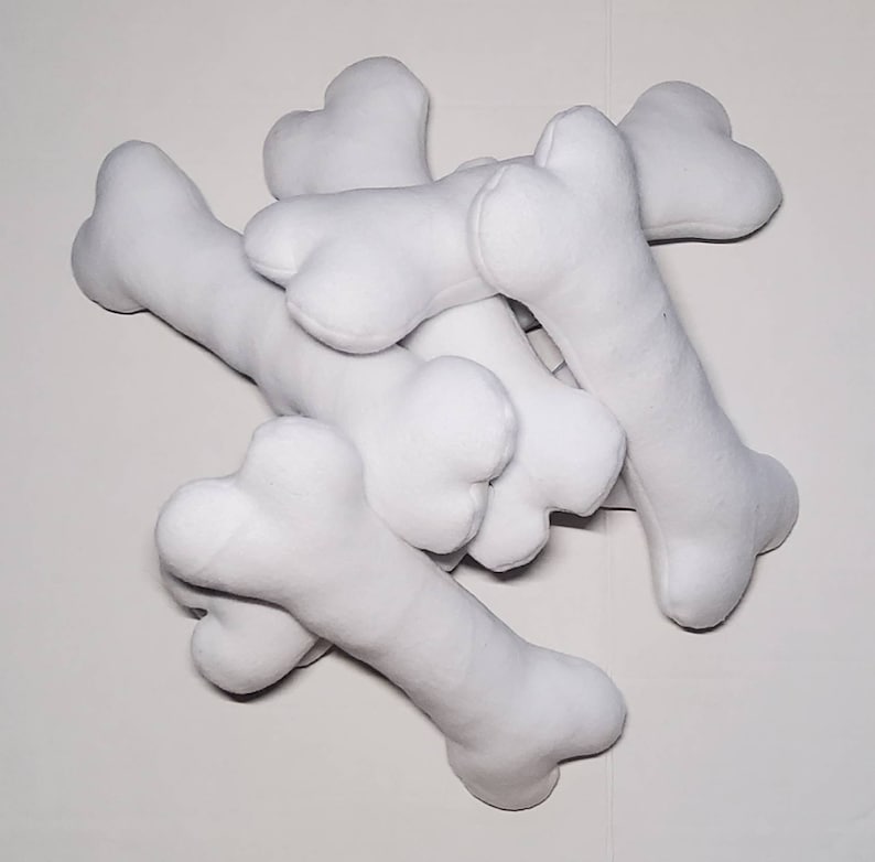 May include: A pile of white plush dog bones. The bones are soft and cuddly, perfect for a dog to play with.