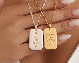 Puede incluir: Dos collares con colgantes rectangulares en cadenas finas. Un colgante de tono plateado está grabado con el texto P.S. I still love you. El otro colgante de tono dorado está grabado con el texto forever and always y un pequeño corazón.
