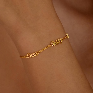 May include: A gold chain bracelet with the names "Sean" and "Teddy" spelled out in cursive.
