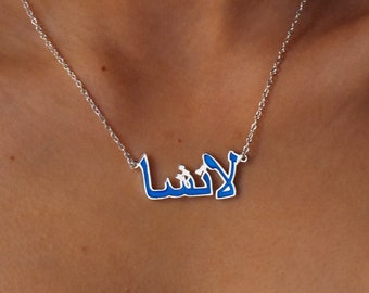 May include: A silver chain necklace with a blue enamel pendant that says "Laysha" in Arabic script.