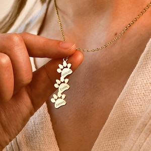 May include: Gold necklace with a pendant featuring four paw prints with the names William, Emily, and James engraved on them.