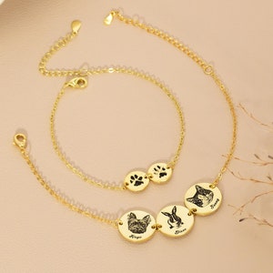May include: Two gold-coloured bracelets. One bracelet features two circular charms with paw prints. The other bracelet has three circular charms with pet portraits and names: a dog, a rabbit, and a cat. The bracelets have adjustable chains.