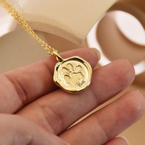 May include: Gold necklace with a paw print charm and the name "Bella" engraved on it.