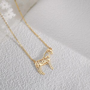 May include: A gold chain necklace with a horse pendant. The horse is made of metal and has the word "Hello" written inside its outline.