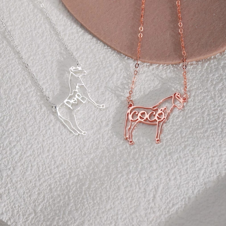 May include: Two silver necklaces with horse pendants. The horse pendants are made of wire and the name "Hope" is spelled out in the wire on one pendant and the name "Coco" is spelled out in the wire on the other pendant.