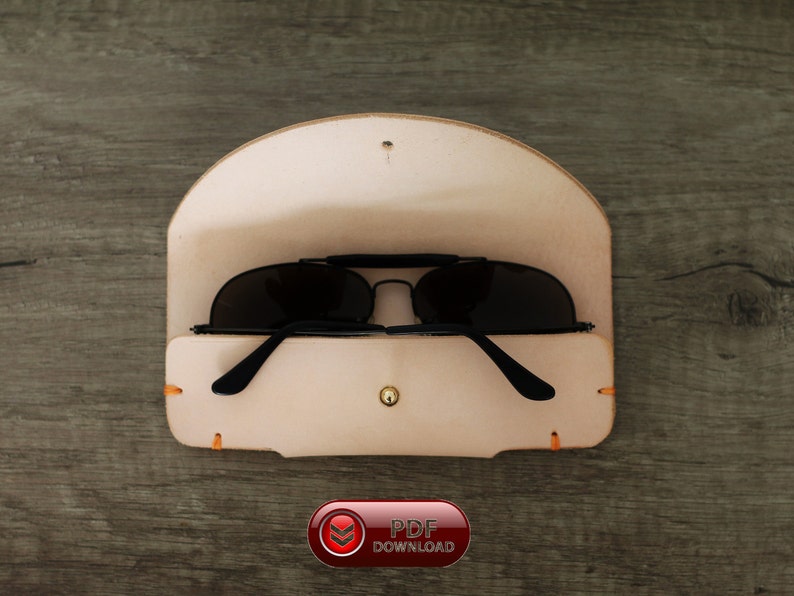 Puede incluir: Un estuche de cuero de color beige claro para gafas de sol con gafas de sol negras en el interior. El estuche est&aacute; abierto, revelando las gafas. El estuche tiene un cierre de bot&oacute;n y costuras naranjas. La imagen tambi&eacute;n incluye un bot&oacute;n rojo con el texto "PDF DOWNLOAD".