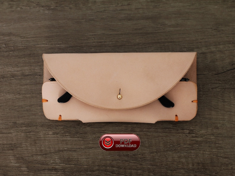 Puede incluir: Un estuche de gafas de cuero de color beige claro con una solapa curva y un cierre de bot&oacute;n de lat&oacute;n. El estuche contiene gafas con montura negra y presenta detalles de costura naranja. La imagen incluye un bot&oacute;n "PDF DOWNLOAD".