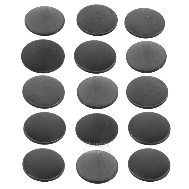 May include: A collection of sixteen round, dark gray coasters. Each coaster has a smooth surface with subtle veining patterns. The coasters are arranged in a grid pattern against a white background. The coasters appear to be made of stone.