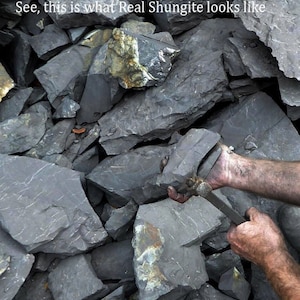 Puede incluir: Primer plano de una pila de rocas gris oscuro. Unas manos sostienen una roca y una herramienta, probablemente para partir la roca. El texto "See, this is what Real Shungite looks like" es visible en la parte superior de la imagen.