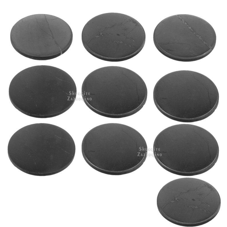 May include: A collection of nine round, dark gray shungite stones. Each stone has a smooth, polished surface with subtle veining. The stones are arranged in a grid pattern, showcasing their natural beauty and unique characteristics.