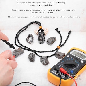 May include: A black braided cord necklace with a shungite pendant. The pendant is a rough, black stone with a silver sheen. The necklace is being tested with a multimeter to show that shungite conducts electricity. The multimeter reads 0.00. The text on the image reads "GENUINE Elite SHUNGITE FROM KARELIA (RUSSIA) CONDUCTS ELECTRICITY. THEREFORE, WHEN MEASURING RESISTANCE TO ELECTRIC CURRENT, WE SEE THAT IT IS ZERO. This UNIQUE PROPERTY of Elite Shungite is PROOF OF ITS AUTHENTICITY."